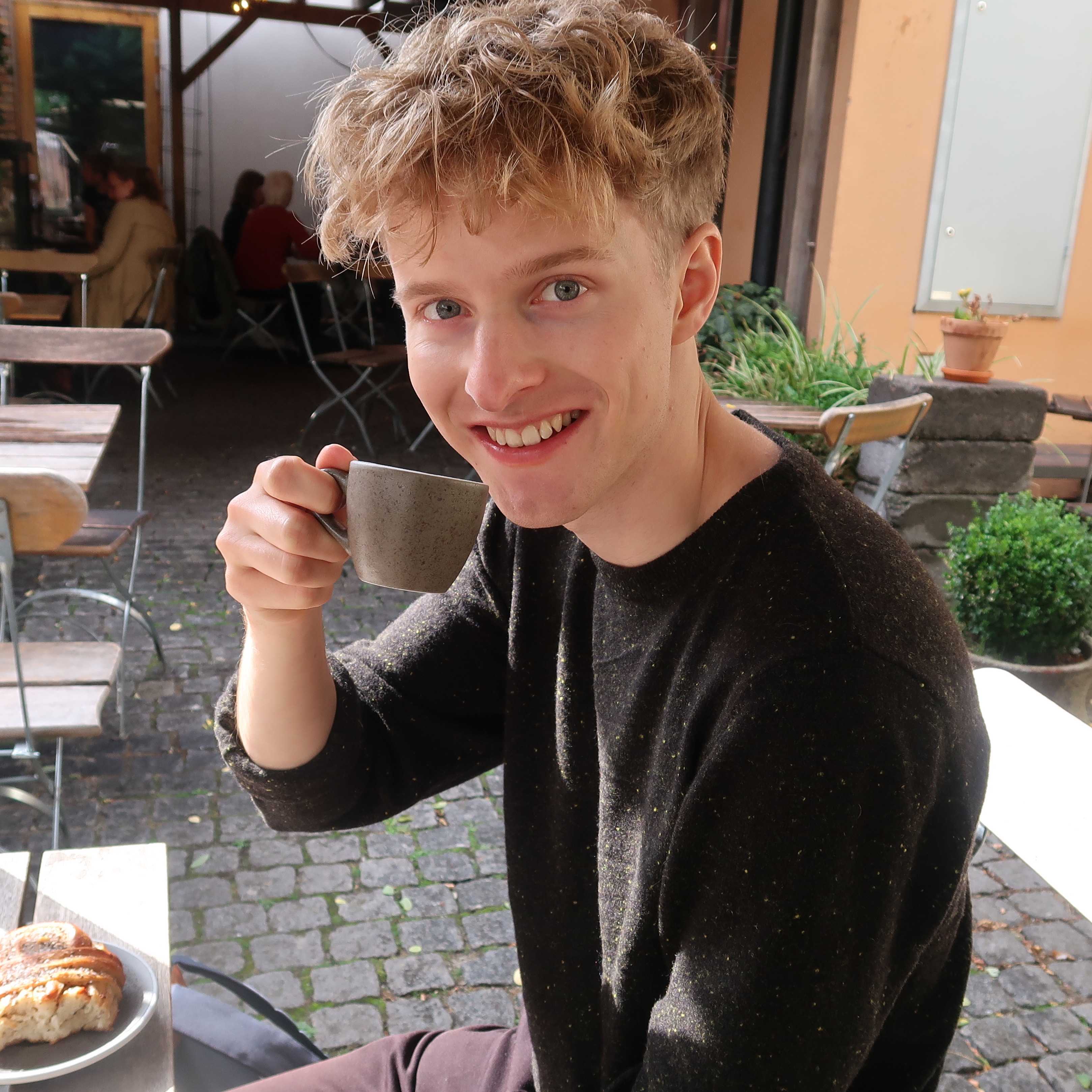 Photo of Arvid with a cup of coffee, smiling.